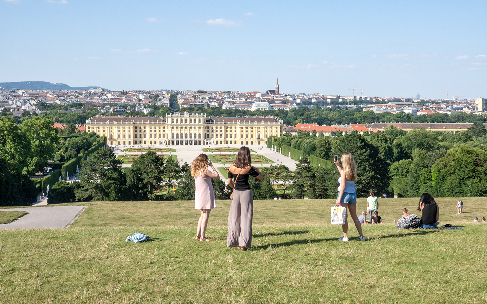 Schönbrunn Palace and gardens in Vienna with visitors enjoying the view.