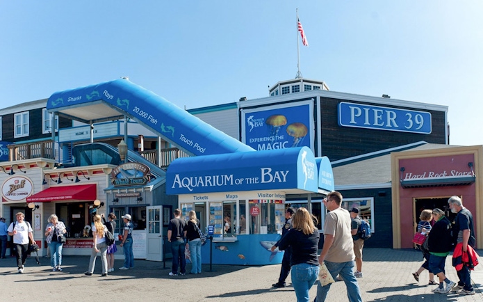Aquarium of the Bay entrance at Pier 39, San Francisco, with visitors walking nearby.