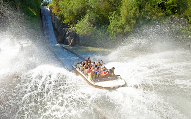 Boat descending water slide at Isla Mágica, creating a large splash.