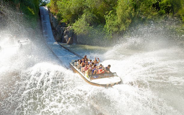 Boat descending water slide at Isla Mágica, creating a large splash.