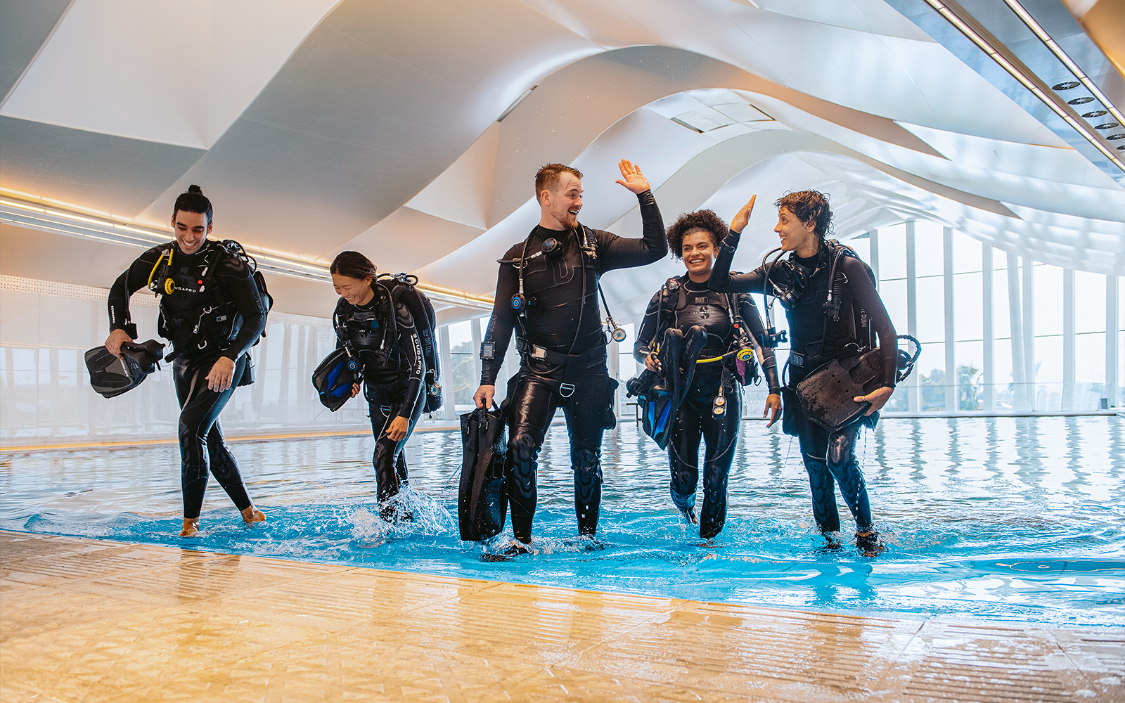 Divers exiting pool at Deep Dive Dubai indoor facility.