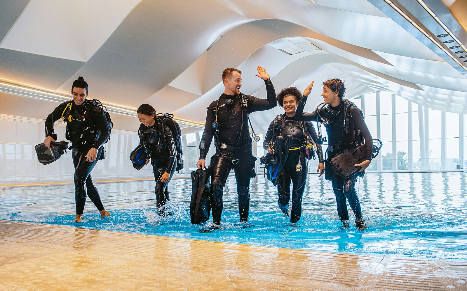 Divers exiting pool at Deep Dive Dubai indoor facility.