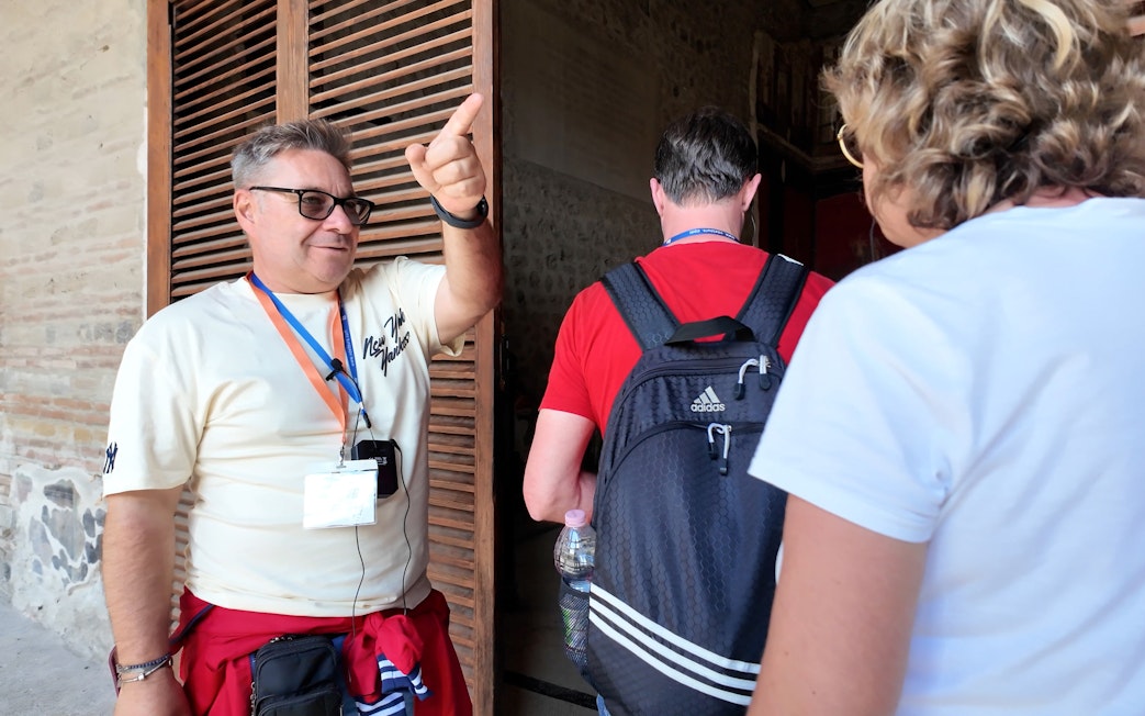Guide leading tourists through Pompeii ruins.