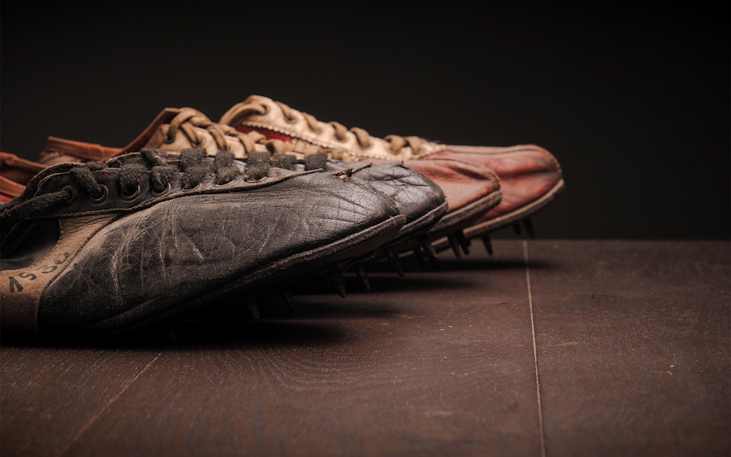 Vintage football boots with worn leather and metal studs on a wooden surface.