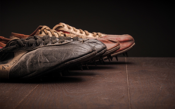 Vintage football boots with worn leather and metal studs on a wooden surface.