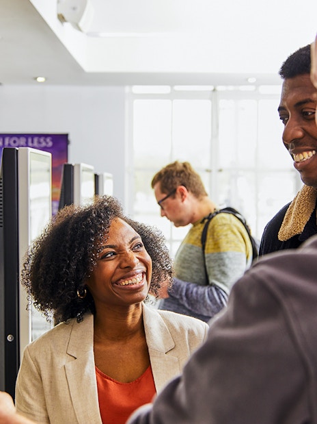 Guide assisting tourists with London Eye tickets at kiosk.