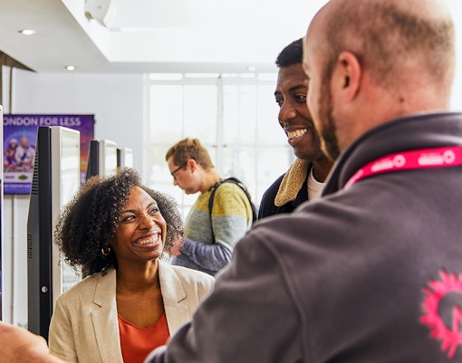 Guide assisting tourists with London Eye tickets at kiosk.