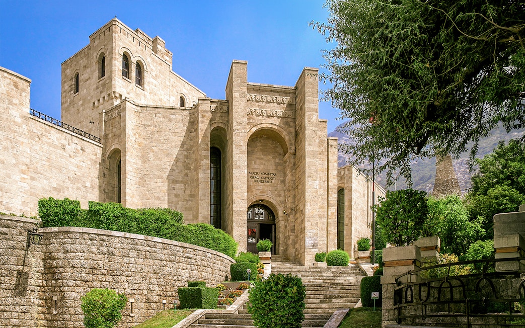 Skanderbeg Museum entrance at Kruje Castle, Albania, with stone architecture and surrounding greenery.
