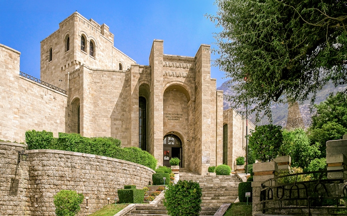 Skanderbeg Museum entrance at Kruje Castle, Albania, with stone architecture and surrounding greenery.