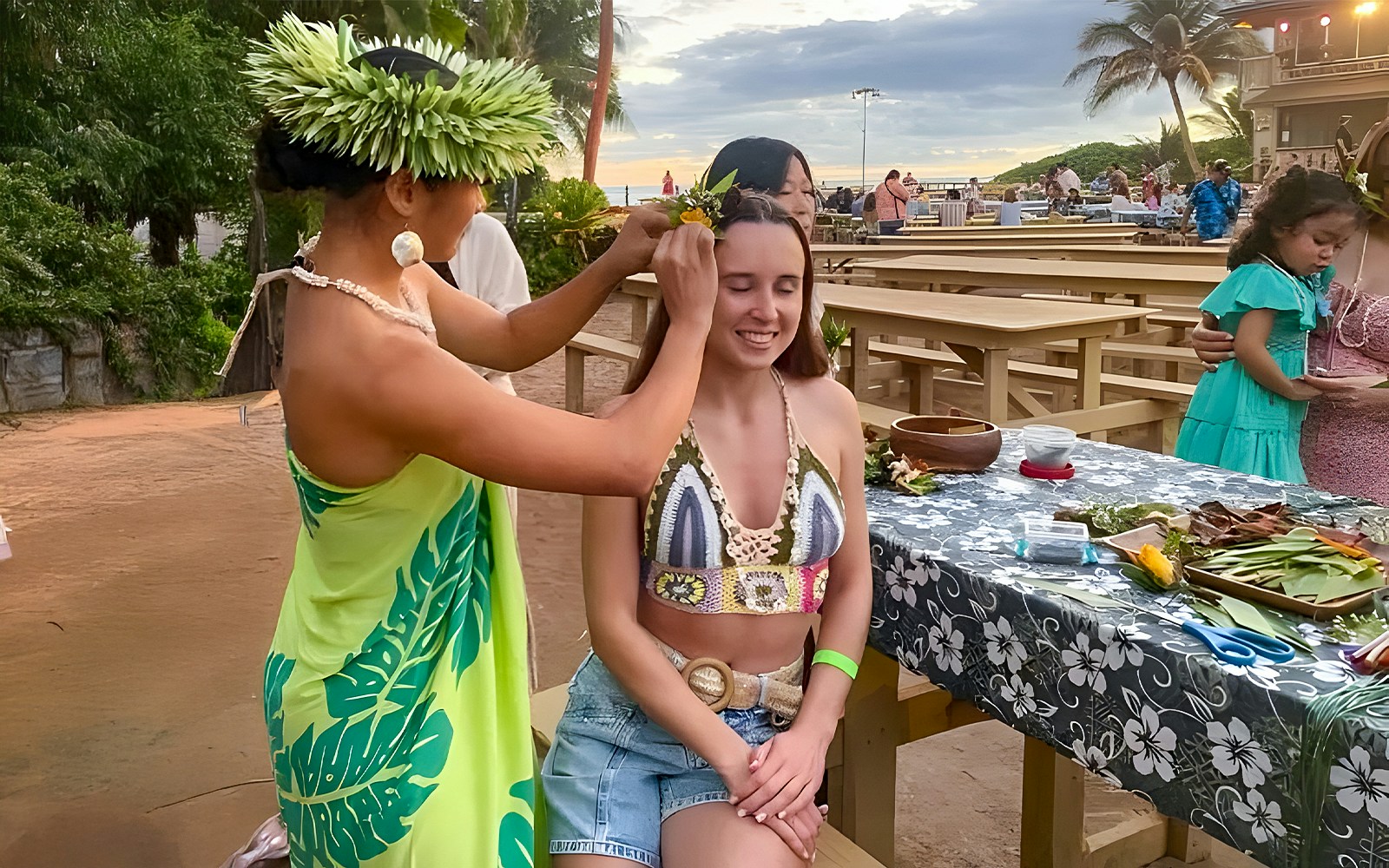 Woman receiving a flower crown at Germaine's Luau pre-show cultural activities.