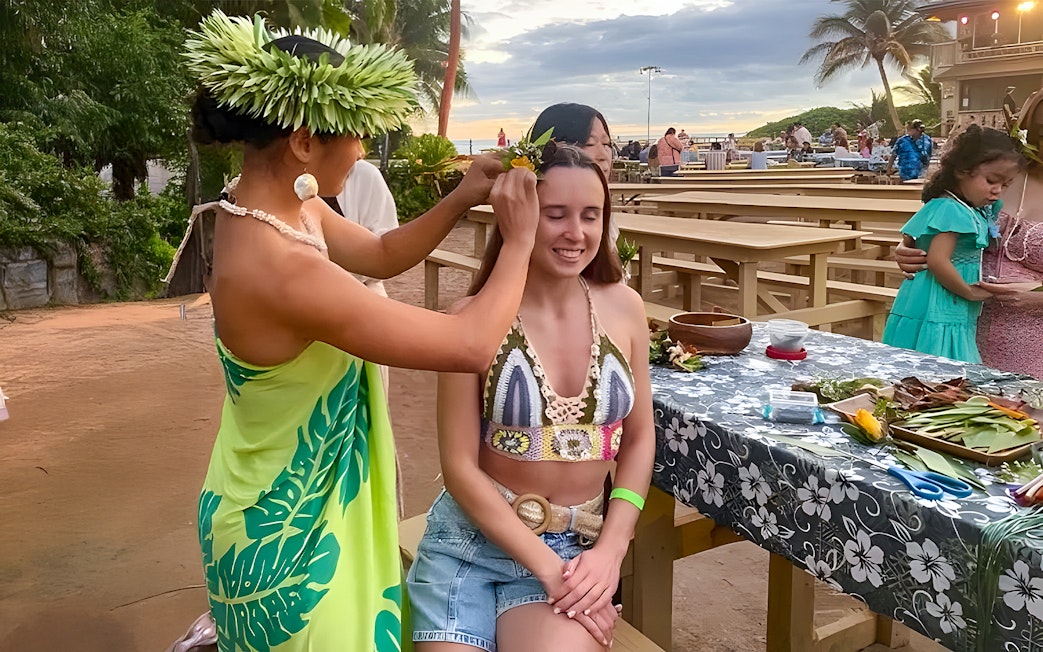 Woman receiving a flower crown at Germaine's Luau pre-show cultural activities.