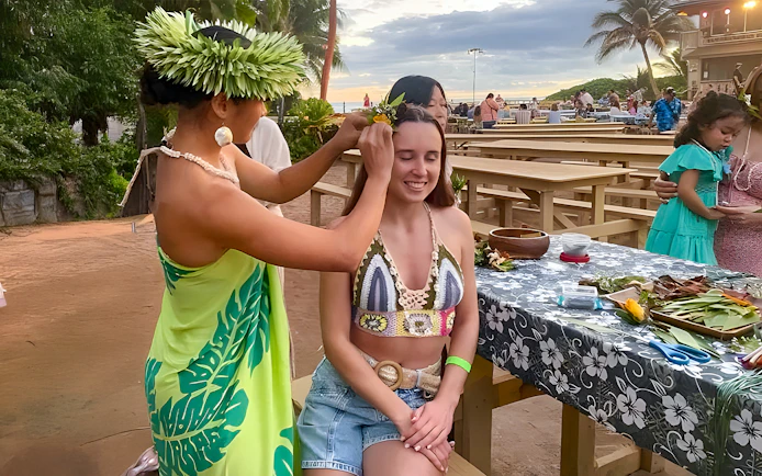 Woman receiving a flower crown at Germaine's Luau pre-show cultural activities.