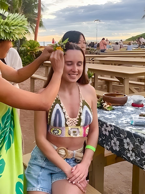 Woman receiving a flower crown at Germaine's Luau pre-show cultural activities.
