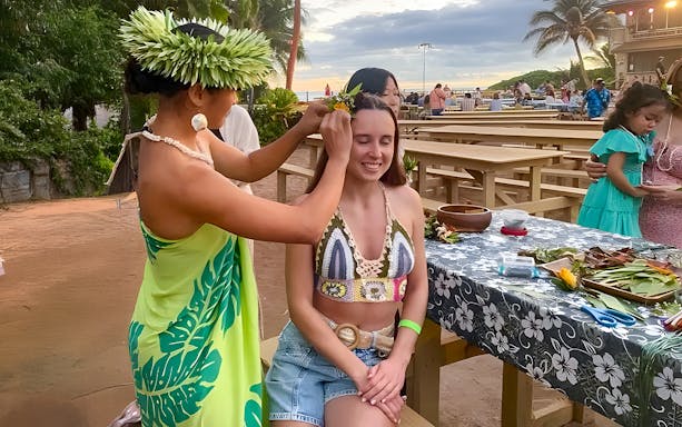 Woman receiving a flower crown at Germaine's Luau pre-show cultural activities.
