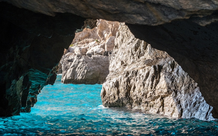 The Green Grotto's turquoise waters and rocky cave entrance in Capri, Italy.