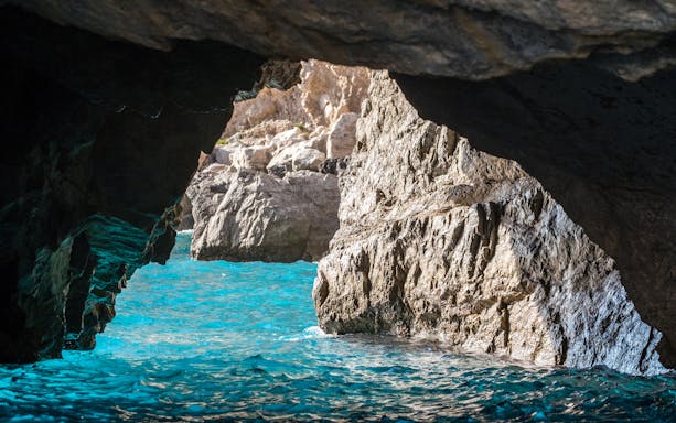 The Green Grotto's turquoise waters and rocky cave entrance in Capri, Italy.