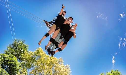 Thrill-seekers on Cairns Giant Swing, soaring through lush rainforest canopy in Queensland, Australia.
