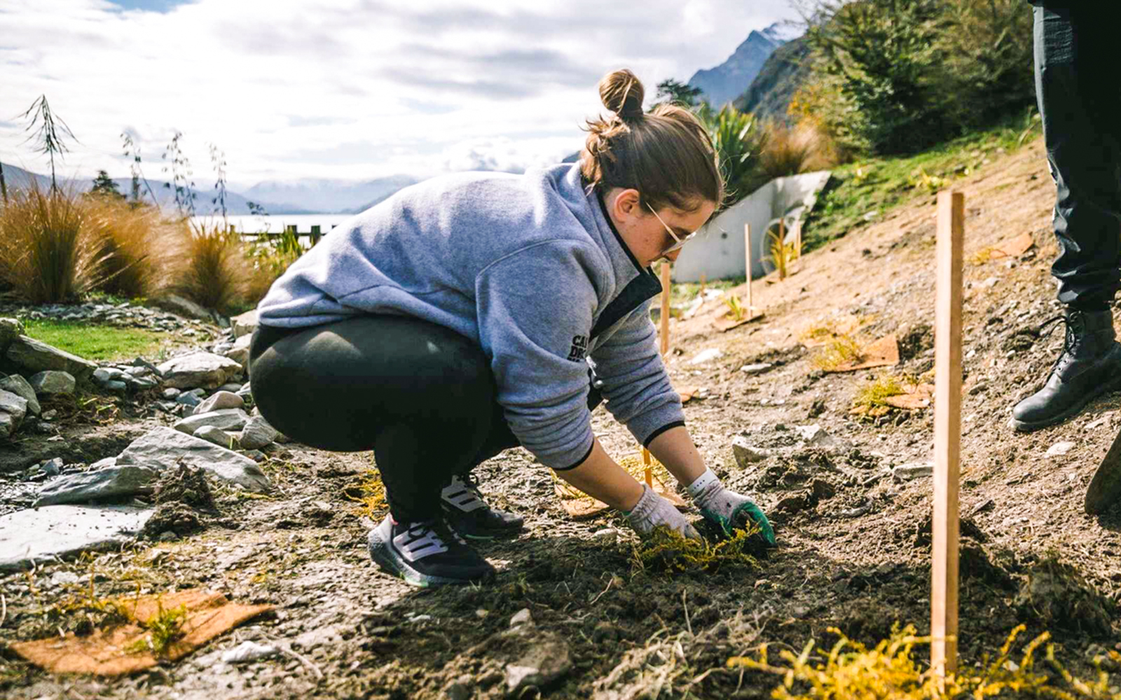 Woman participating in farm activity at Walter Peak, Queenstown, with sheep in the background.