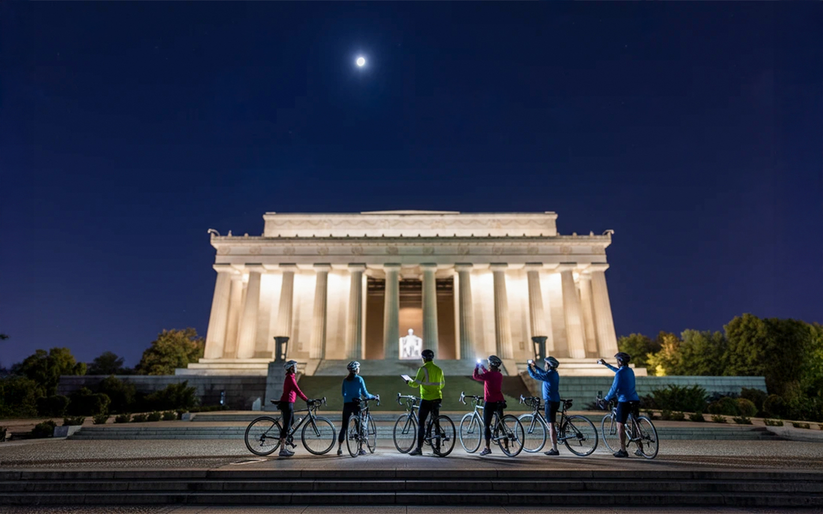 Tourists biking at night near the illuminated Lincoln Memorial, Washington D.C.