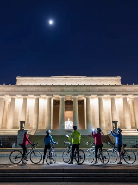 Tourists biking at night near the illuminated Lincoln Memorial, Washington D.C.