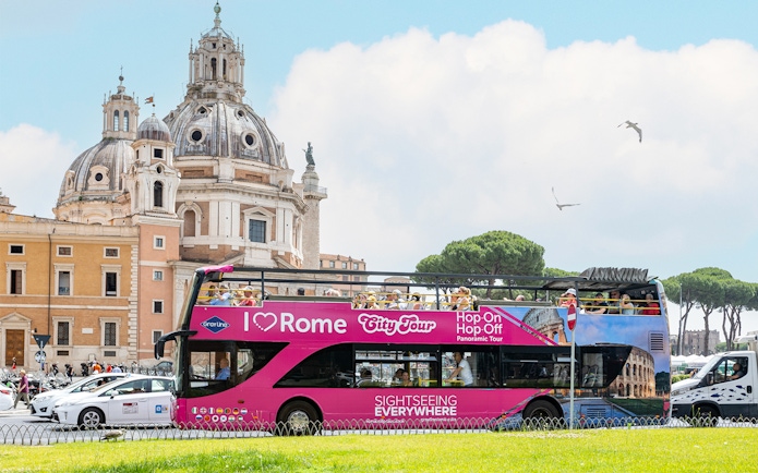 Open-top tour bus in Rome near historical architecture.