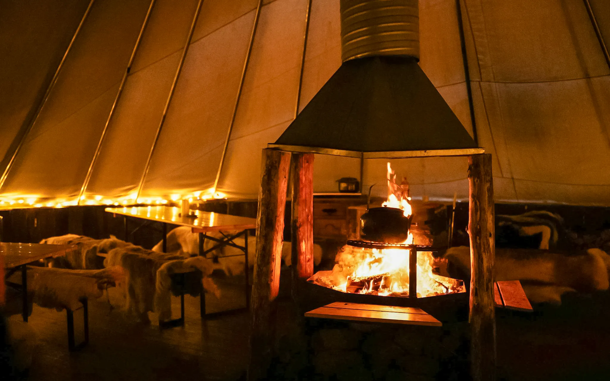 Fireplace inside a tent with benches, part of the Reindeer Encounter & Sámi Culture Experience.