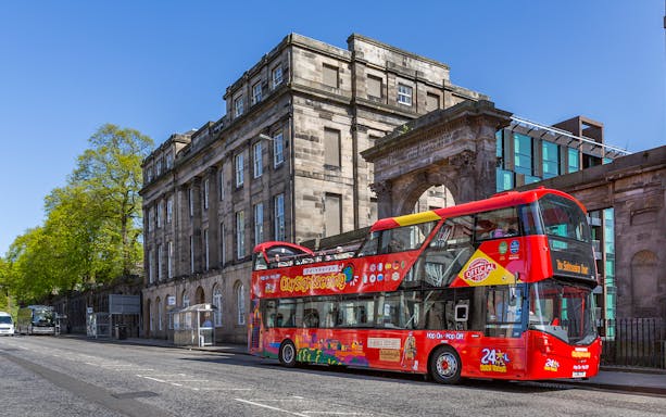 Hop on Hop off bus in front of historic building in Edinburgh.