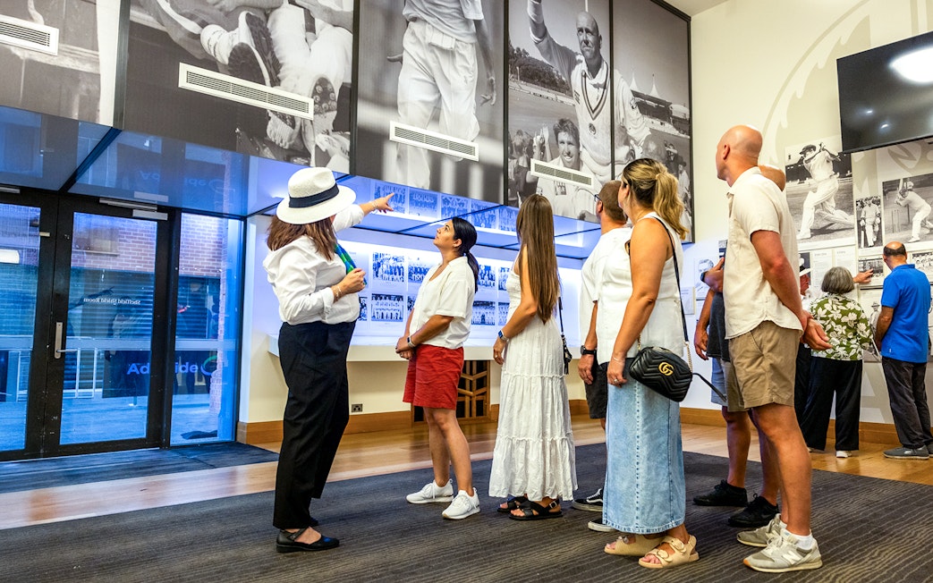 Guide explaining cricket history to visitors at Adelaide Oval Stadium.