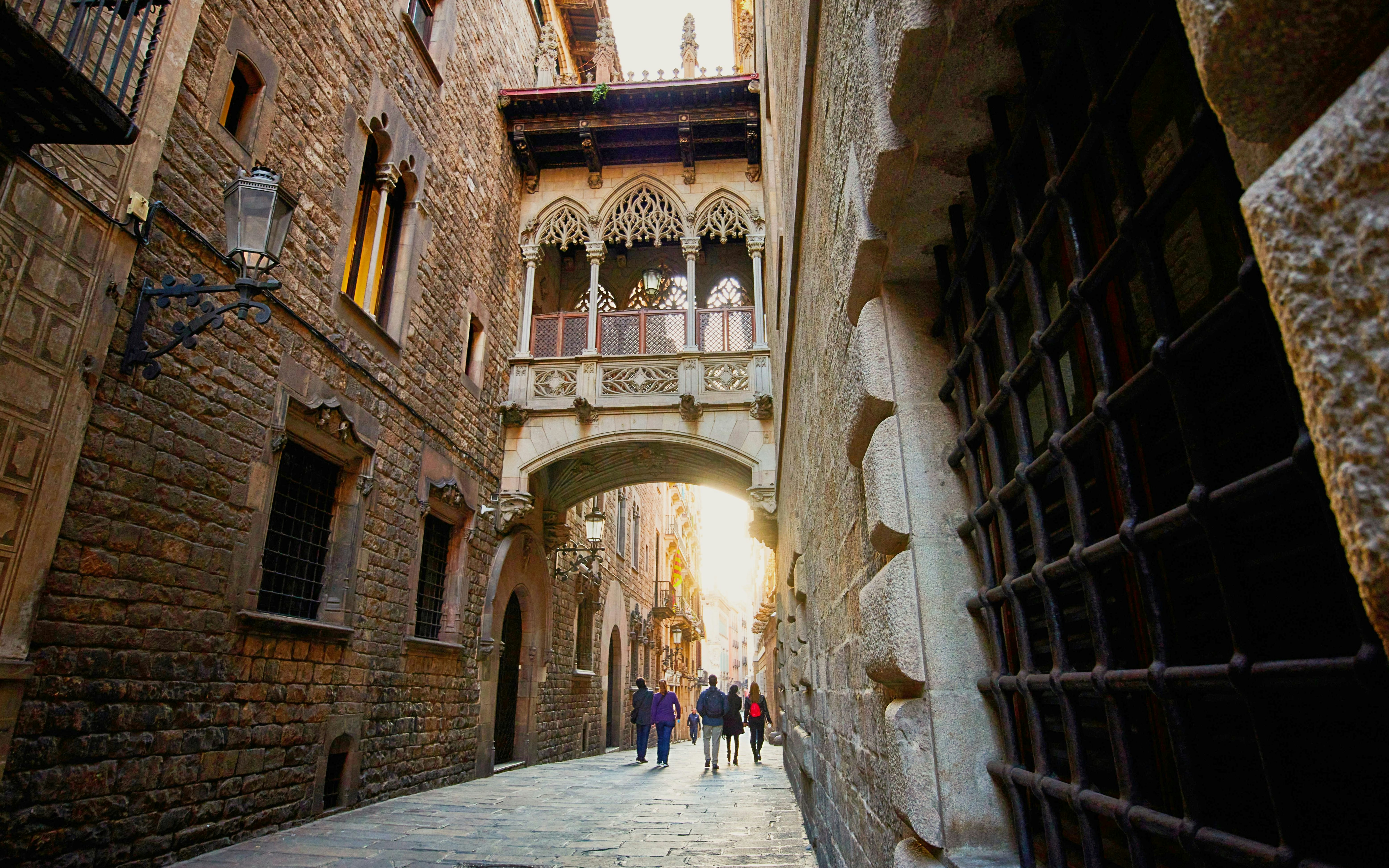 Pont del Bisbe in Barcelona's Gothic Quarter with pedestrians walking below.