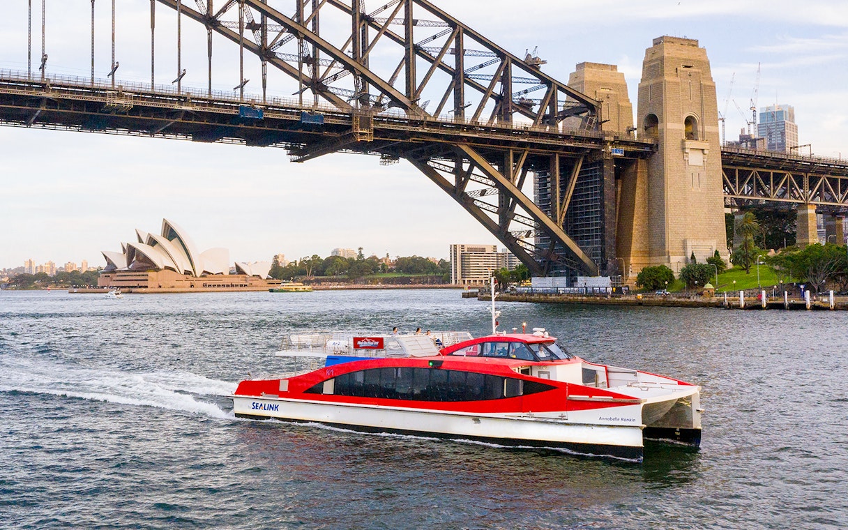 Sydney Harbour cruise boat near Sydney Opera House and Harbour Bridge.
