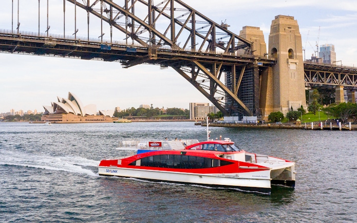 Sydney Harbour cruise boat near Sydney Opera House and Harbour Bridge.