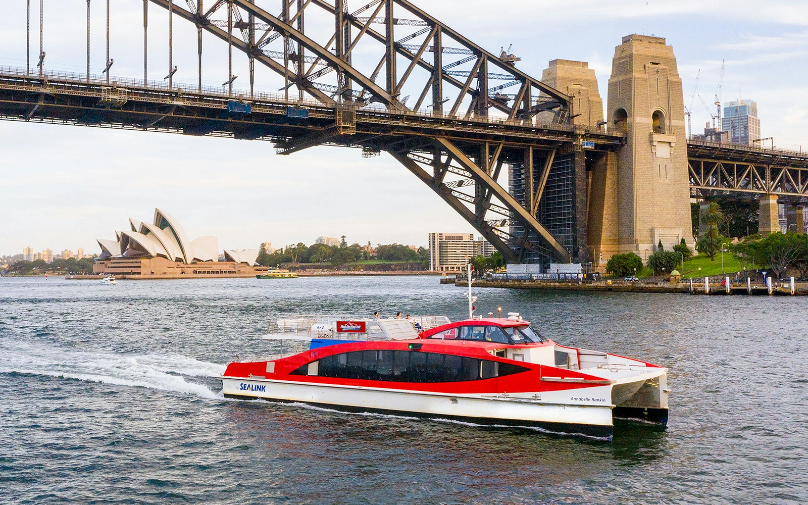 Sydney Harbour cruise boat near Sydney Opera House and Harbour Bridge.