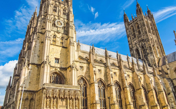 Canterbury Cathedral's Gothic architecture under a blue sky.