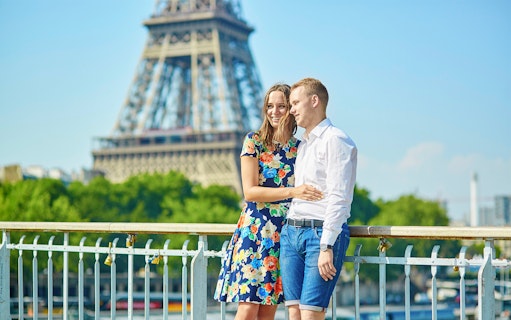 Couple on a Parisian bridge with Eiffel Tower in the background during a private photo tour.