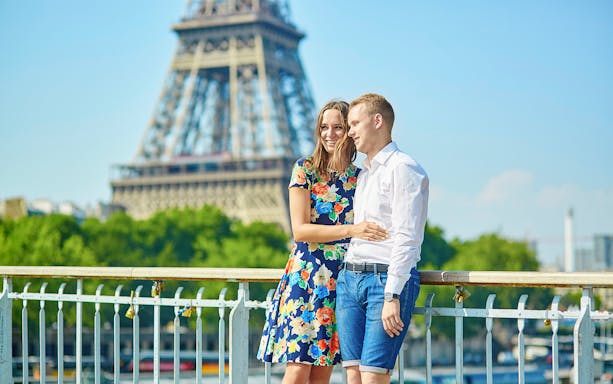 Couple on a Parisian bridge with Eiffel Tower in the background during a private photo tour.