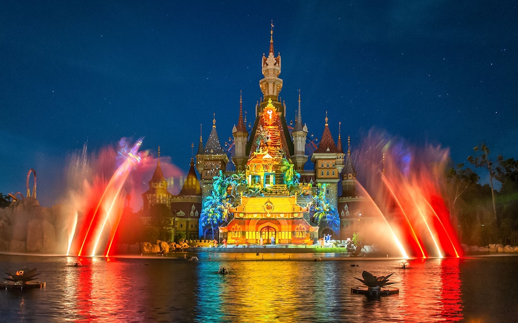 VinWonders castle illuminated with colorful lights and water fountains at night.