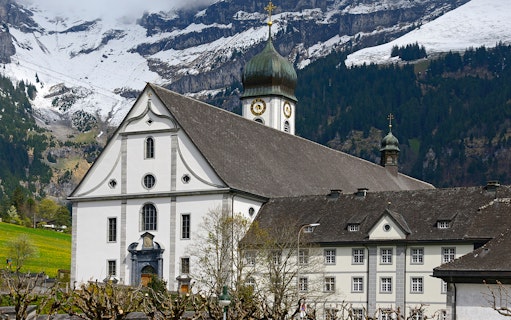 Engelberg Abbey with snow-capped mountains in the background, part of Zurich to Mt. Titlis tour.