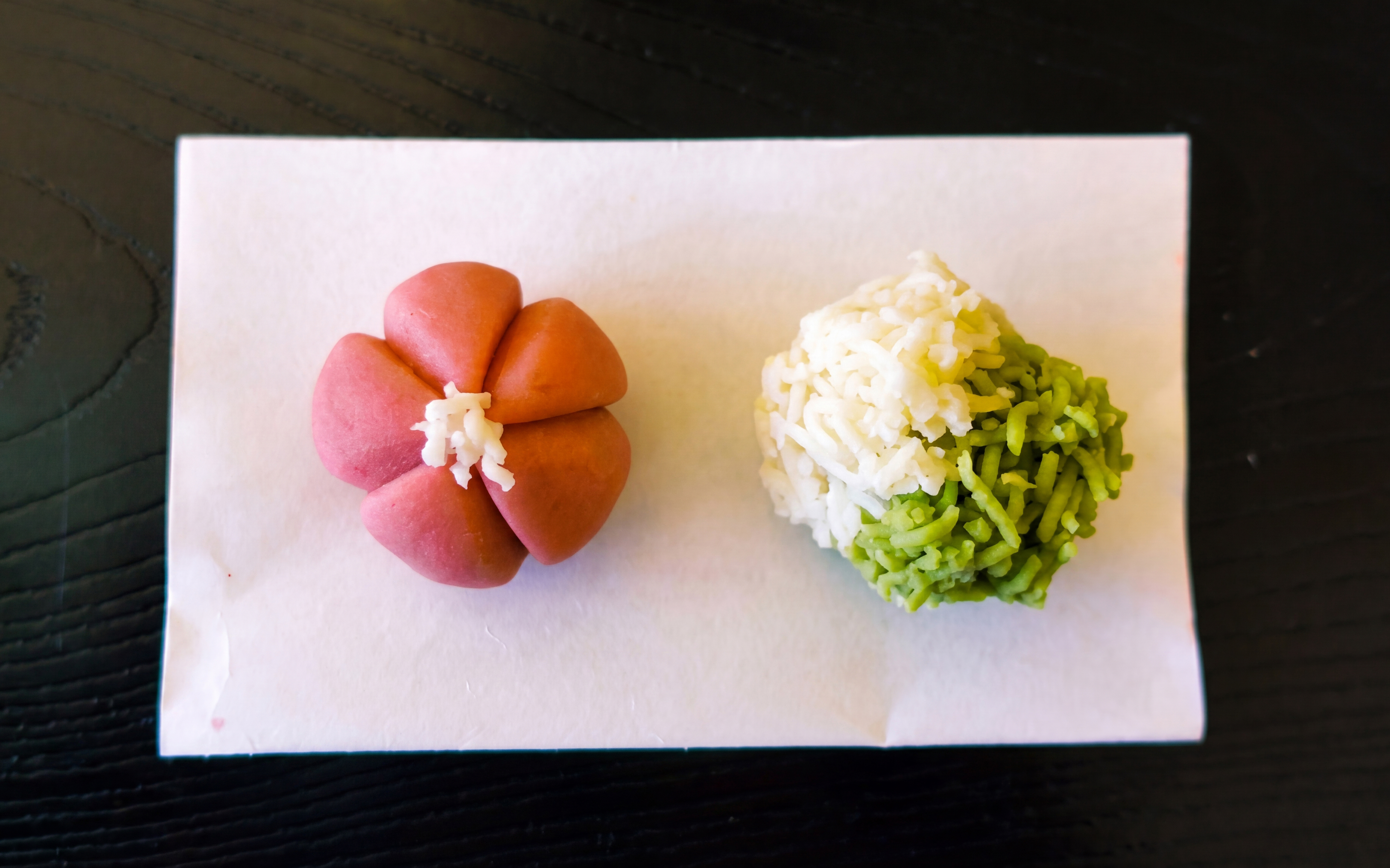 Kyoto traditional sweets on paper, featuring a pink flower-shaped sweet and a green-white rice ball.