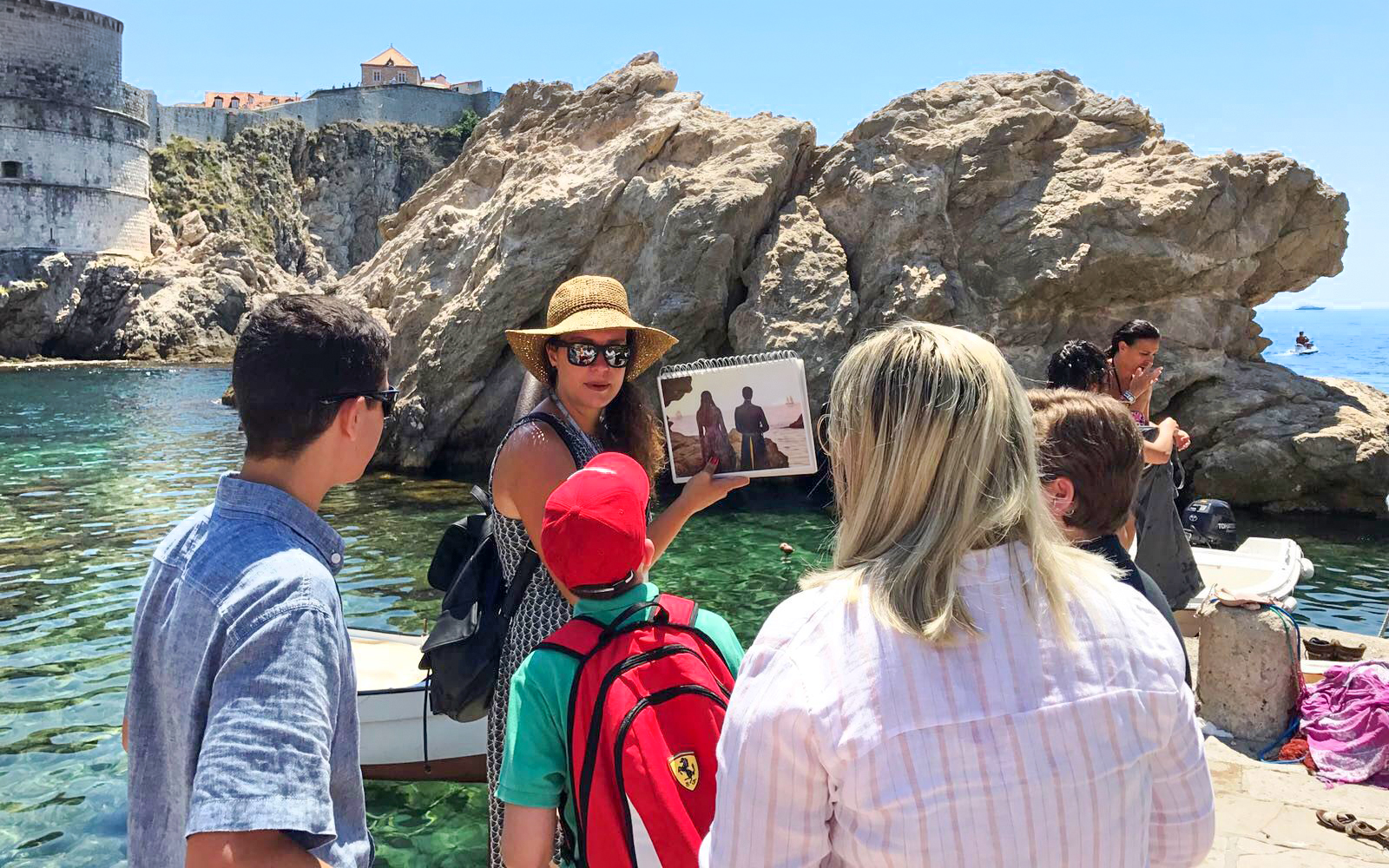Tour guide showing Game of Thrones scene to group by Dubrovnik's historic walls.