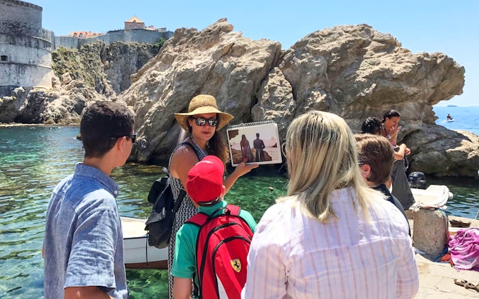 Tour guide showing Game of Thrones scene to group by Dubrovnik's historic walls.