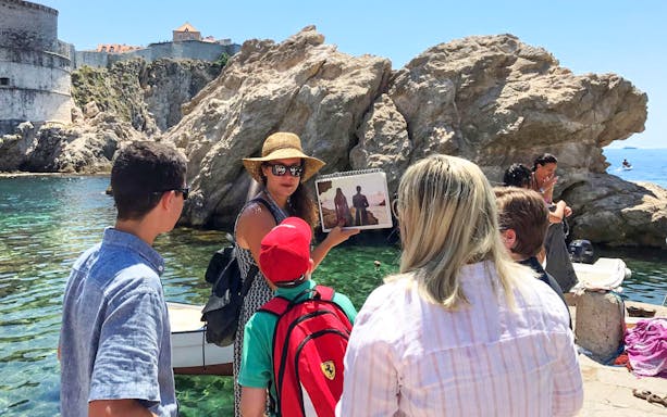 Tour guide showing Game of Thrones scene to group by Dubrovnik's historic walls.