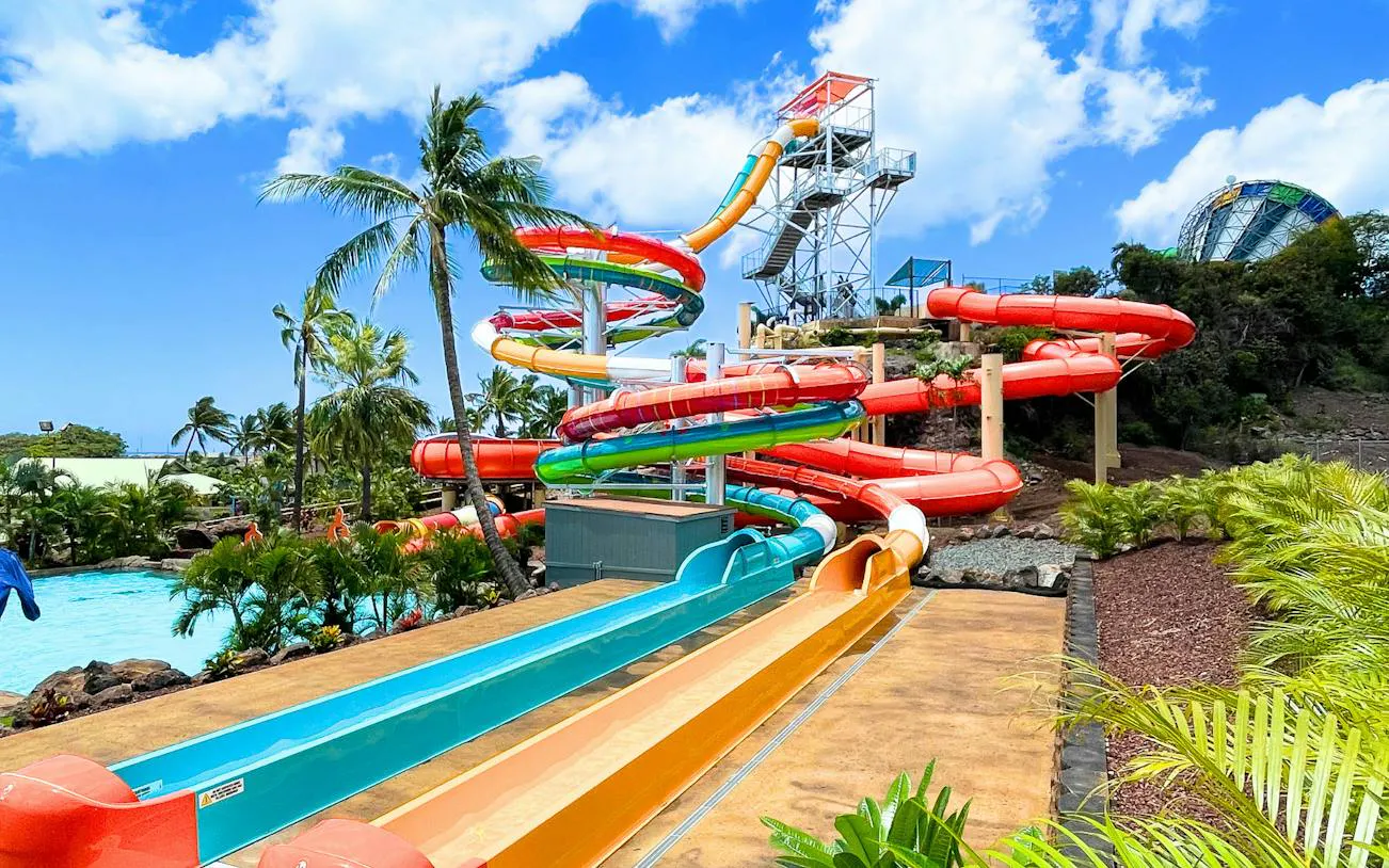 Colorful water slides at Wet 'n' Wild Hawaii, Oahu, surrounded by palm trees and clear skies.