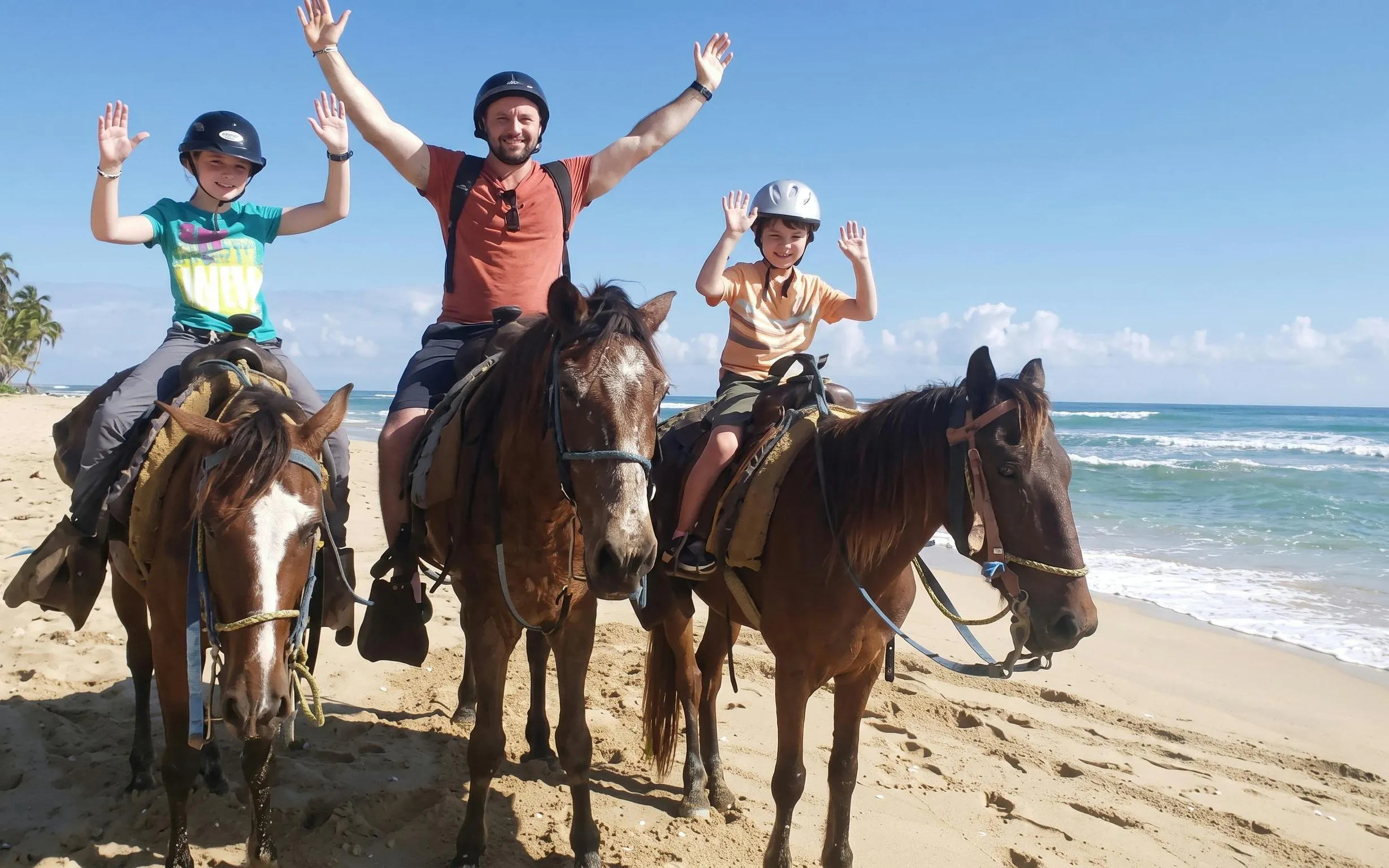 Three people horseback riding on Macao Beach with ocean in the background.