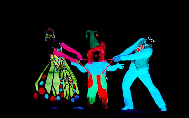 Performers in neon costumes at WOW Show Black Light Theater, Prague.