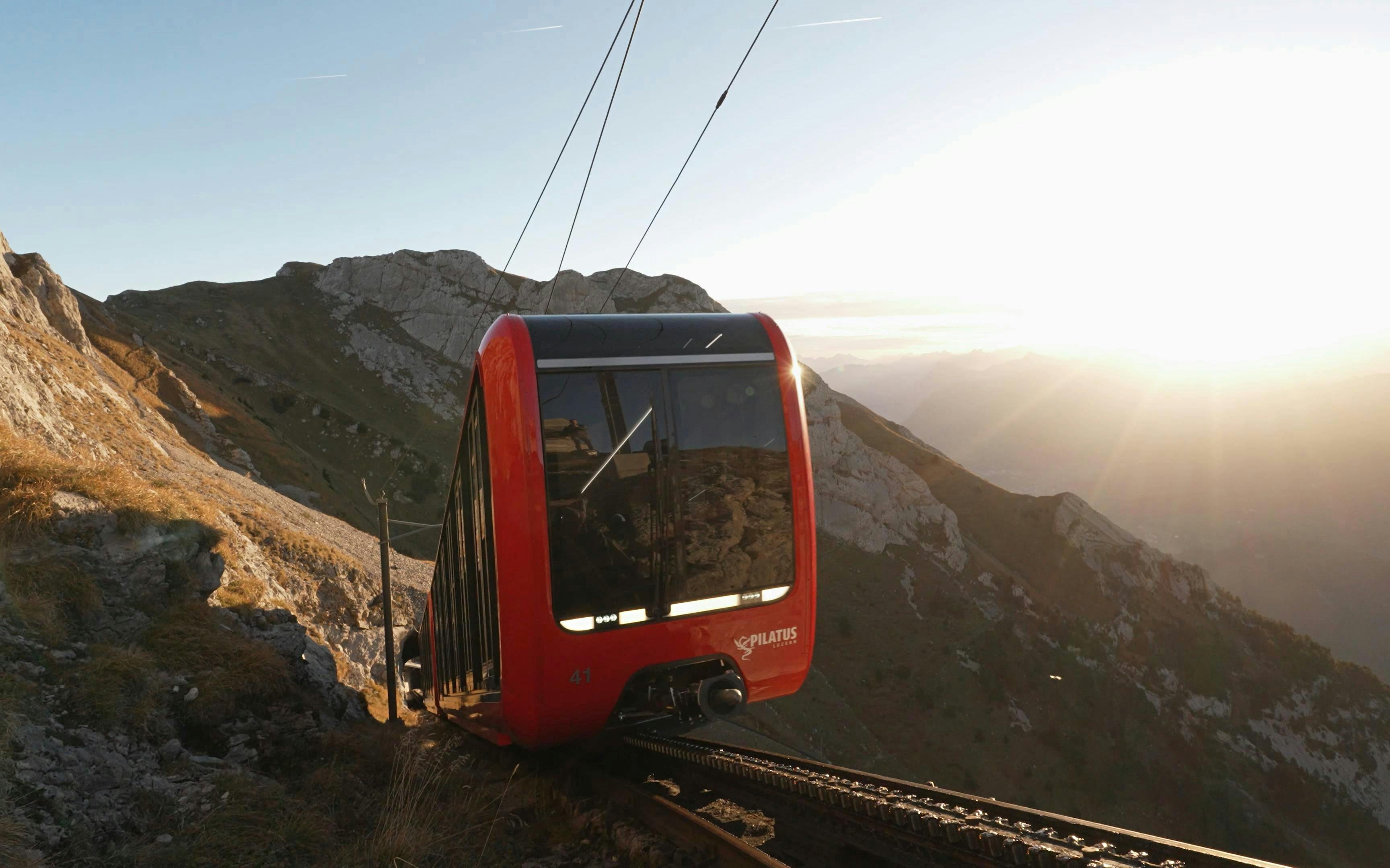 Pilatus cogwheel railway ascending mountain at sunrise in Switzerland.