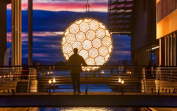 Silhouette of a person viewing illuminated art installation during Amsterdam Light Festival canal cruise.