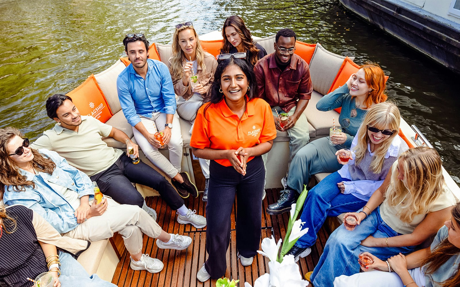 Luxury open boat cruise on Amsterdam's canals with passengers enjoying drinks.