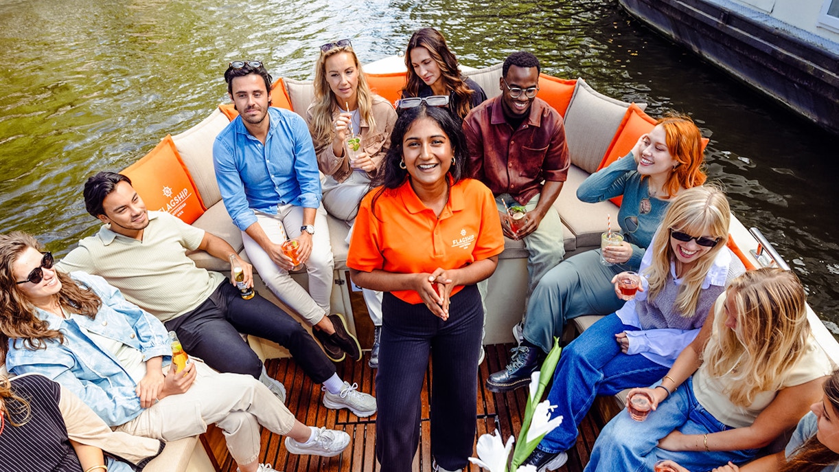 Group enjoying drinks on a luxury open boat cruise in Amsterdam canal.