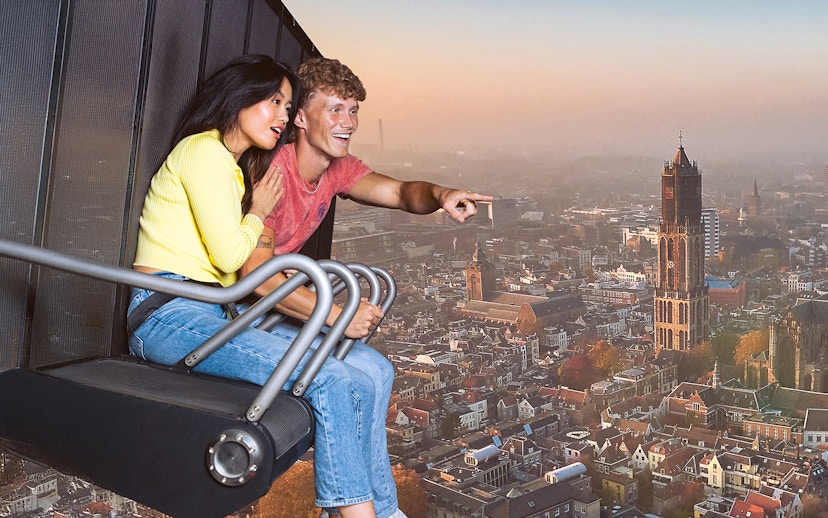Tourists on 5D ride at This Is Holland, viewing aerial cityscape.