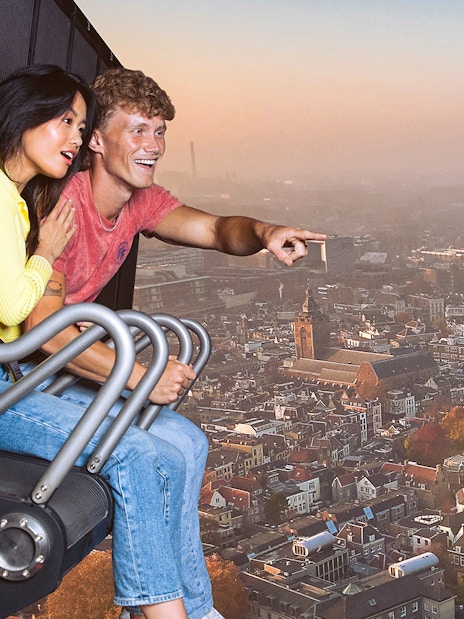 Tourists on 5D ride at This Is Holland, viewing aerial cityscape.